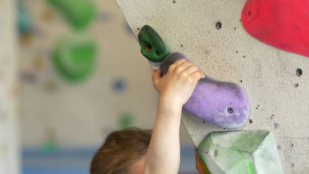 jovem caucasiana escalando parede de escalada interior perto - climbing wall rock climbing holding reaching - fotografias e filmes do acervo