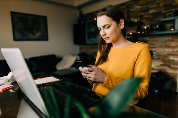 istock Young woman working from home and using a laptop and a smartphone 1644326616