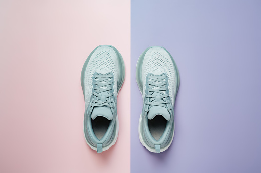 New light blue green female modern running shoe on pink purple geometrical background. Stylish monochrome shoes for active people that incorporate new health technology. Top view