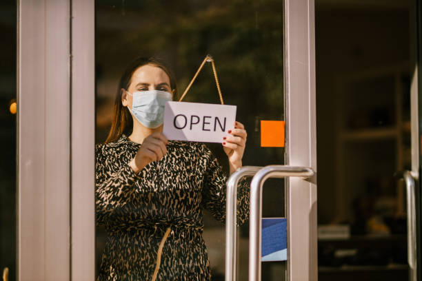 istock Woman wearing a protective mask is opening a store 1644330741