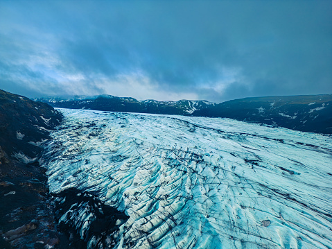 Stunning Vatnajokull glaciers with chunks of ice and large icy surfaces within nordic wilderness, drone shot. Diamond shaped iceberg with frozen water close to frost covered mountains.