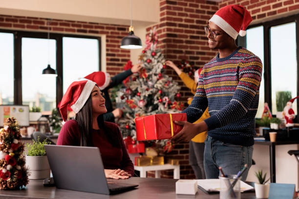 un travailleur offre un cadeau de noël à un collègue - christmas office gift people photos et images de collection