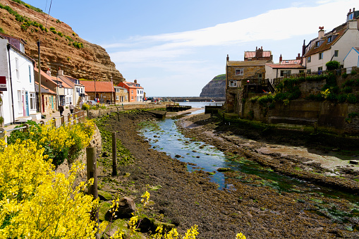 Staithes, England - 24 May 2023: A small number of locals and visitors to Staithes and Cowbar take advantage of the spring sunshine.