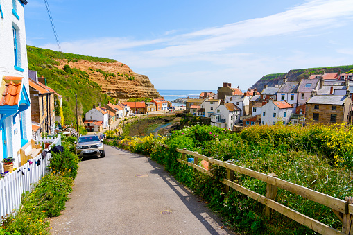 Cowbar, England - 24 May 2023: Steep, narrow road leads down to Staithes harbor and the North Sea.