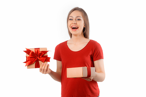 Smiling funny child (kid, girl) in Santa red hat holding Christmas gift in hand. Christmas concept.