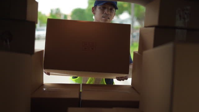 Delivery man take a package box in to transport van and checking inventory to prepare delivery to customer.