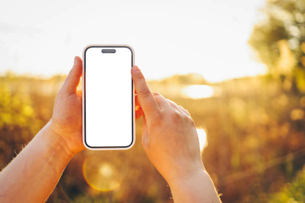 istock Phone in hands with isolated screen at sunset 1644400580
