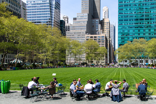 New York City, NY, USA-May 2022; View of the lawn of Bryant Park in Midtown Manhattan with tables filled with people having al fresco lunch