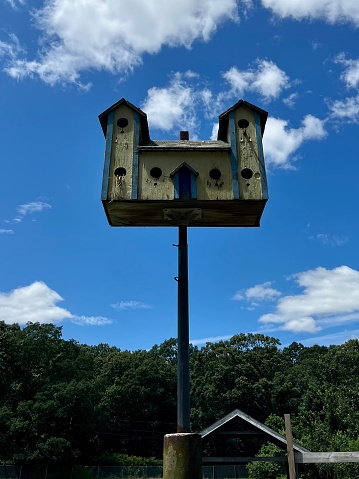 A collection of four colorful home made wooden bird houses with a jar of wildflowers on a Cape Cod porch.