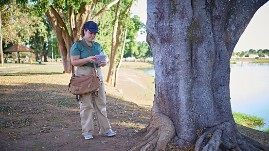 Portrait of a female biologist examining a tree and analysing it, in order to make notes of it for an environmental research.
