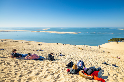 Tourists family sitting on the top of the Dune du Pilat during summer in La Teste de Buch, France