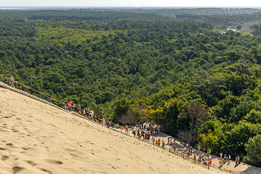 Many tourists climbing the staircase and visiting the Dune du Pilat on a summer day in La Teste-de-Buch, France