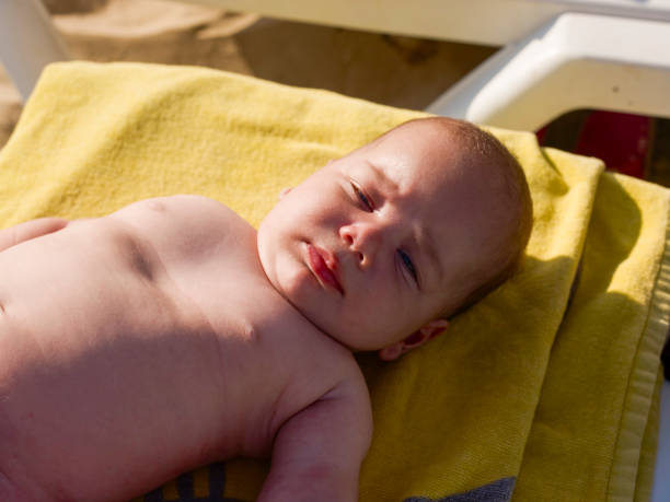 Cute baby boy lying on sunbed at the beach. Baby lying on yellow towel. A sunny day. 3 month old baby boy.