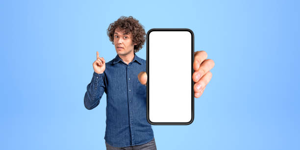 istock Man college student with curly hair showing smartphone with blank screen 1644445818