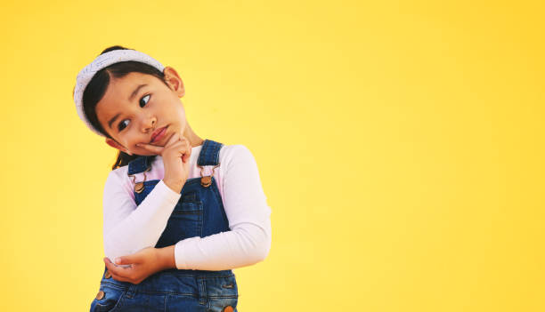 istock Confused, thinking and kid in doubt, decision and studio isolated on yellow background mockup space. Question, idea and girl child trying to remember memory, solution or choice, why and brainstorming 1644448462
