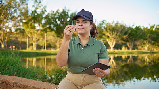Portrait of a biologist examining water sample from a natural park.