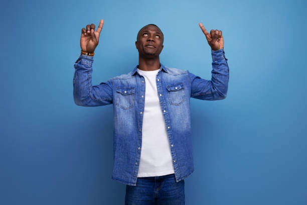 istock handsome young american man in denim jacket pointing with hand at advertising space 1644458043