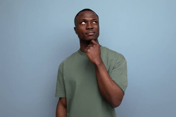 istock young smart african guy with short haircut dressed in a basic t-shirt offers an idea on the background with copy space 1644458635