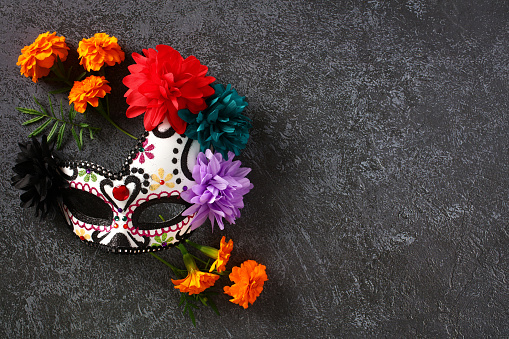Day of the dead, Dia de los muertos skull mask with cempasuchil flowers on stone table.
