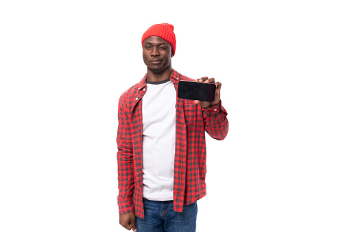 handsome young american man in red headwear showing advertisement on smafton with mockup on isolated white background with copy space.