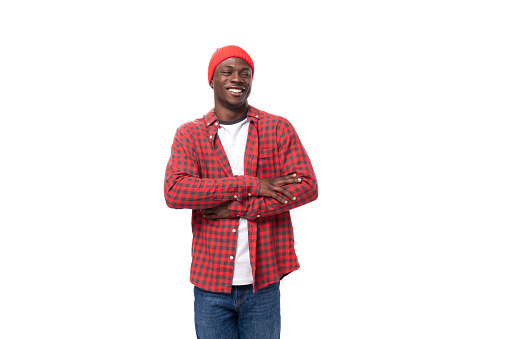 successful confident young american man in red cap and plaid shirt shows calm on white background with copy space.