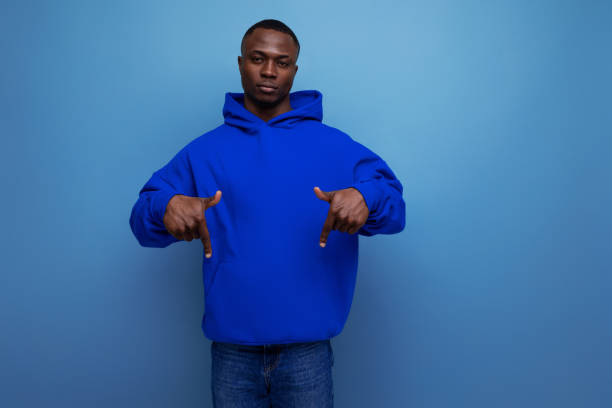 istock confident dark-skinned young american man in a blue sweatshirt shows his hand at an advertisement on a studio background with copy space 1644476176