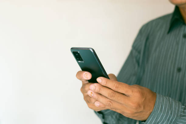 istock Close-up shot of male hand using smartphone on white background. 1644483895