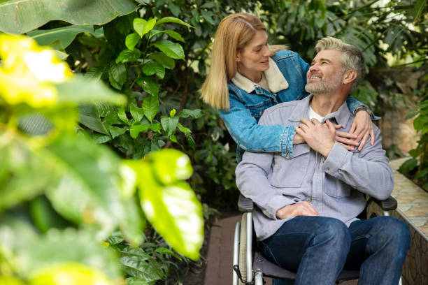 istock Smiling woman rolling a wheelchair and hugging her disabled husband 1644484531