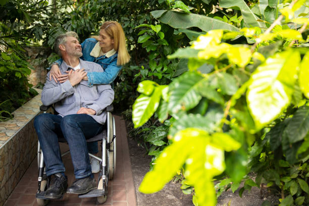 istock Smiling woman rolling a wheelchair and hugging her disabled husband 1644484535