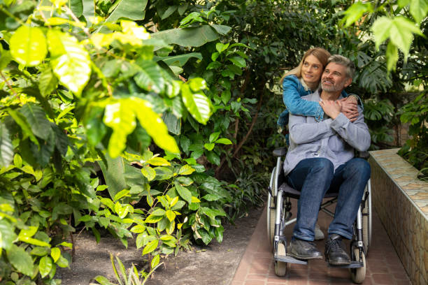 istock Smiling woman rolling a wheelchair and hugging her disabled husband 1644485087