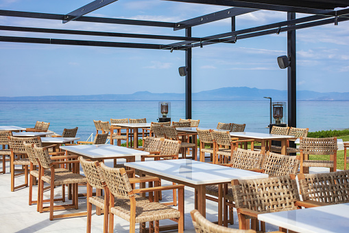 Rattan chairs with tables in a Greek restaurant by the sea.