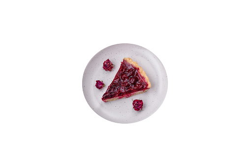 Delicious fragrant sweet pie with cherry berries on a ceramic plate on a dark concrete background