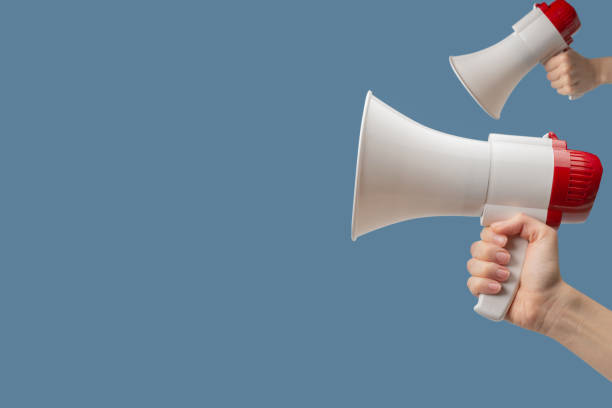istock Megaphone in woman hands on a blue background. 1644487968