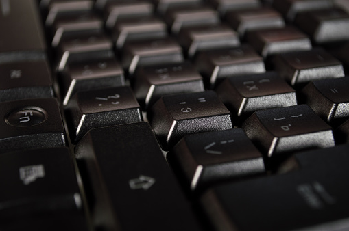 Abstract background of black computer keyboard. Closeup photo with bokeh, can be used like a wallpaper.