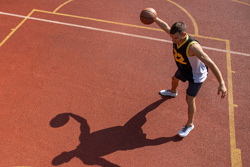 Athletic male sportsman playing basketball throwing ball at playground, copy space.