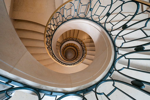Paris, France - 08 26 2023: View of a circular stone staircase and iron stair railing seen from above