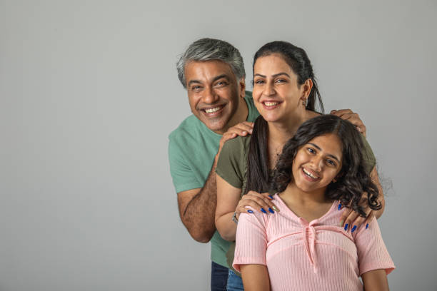 istock Loving parents embracing daughter over white background 1644528416