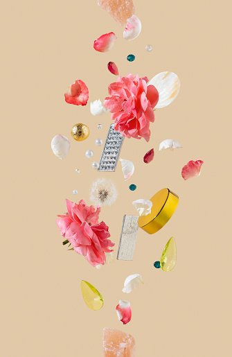 Creative levitating composition of coral pink roses, Himalayan pink salt crystals, white and pink petals, gold, turquoise and white beads, dandelion, gold prism cylinder, marble medalion and zircon metal tile over a beige background.