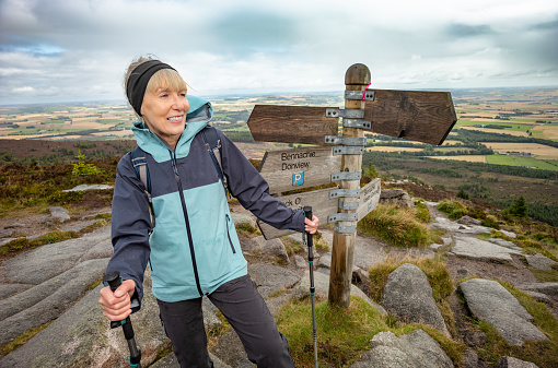Female hiker on a well loved small hill called Bennachie near Inverurie in the Aberdeenshire region of Scotland. This is at the indicator post below the remains of the old Fort.