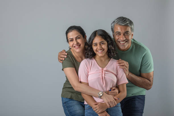 istock Loving parents embracing daughter over white background 1644531343