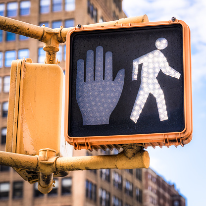 Close-up on a walk / don't walk light for pedestrians in Midtown 
Manhattan, New York City, with the walk symbol illuminated.