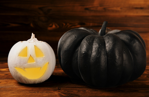 Halloween pumpkin on brown wood texture with candles. Composition on a dark background. Scary composition with glowing eyes and mouth. Holiday concept. copy space