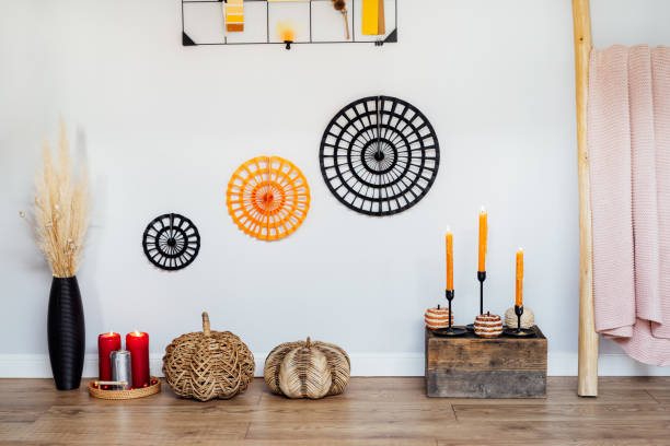 istock Cozy autumn eco-friendly home interior decor- various decorative wicker pumpkins, burning candles, dried flowers in vase on wooden floor and gray wall background. Autumnal Mood inspiration. 1644553179