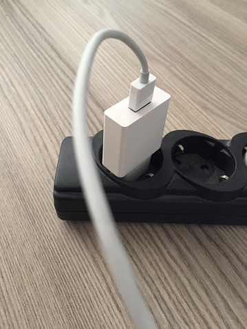 Smart phone charger in extension cord on the wood table