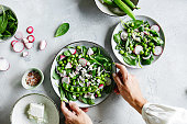Point of view of a woman hands with a plate of healthy vegetable salad on white table