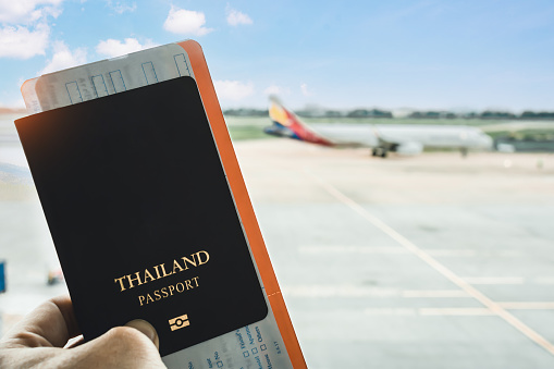 Travel concept. Closeup of man hand holding Thai passport ready to boarding, copy space for text.