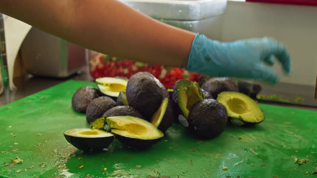 Restaurant Worker Cutting Open Avocados on Cutting Boardc in a Mexican Restaurant