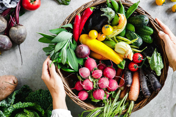 台所のテーブルの上に新鮮な野菜がいっぱい入ったバスケットを持つ女性の視点 - vegies vegetable basket residential structure ストックフォトと画像