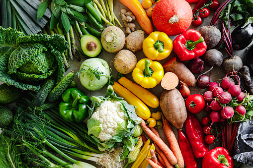 Assortment of various types of vegetables arranged in a rainbow gradient pattern. Full frame of different types of fresh vegetables on table.