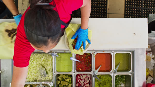 Overhead Shot of Restaurant Worker Adding Toppings to Tacos Inside Mexican Restaurant